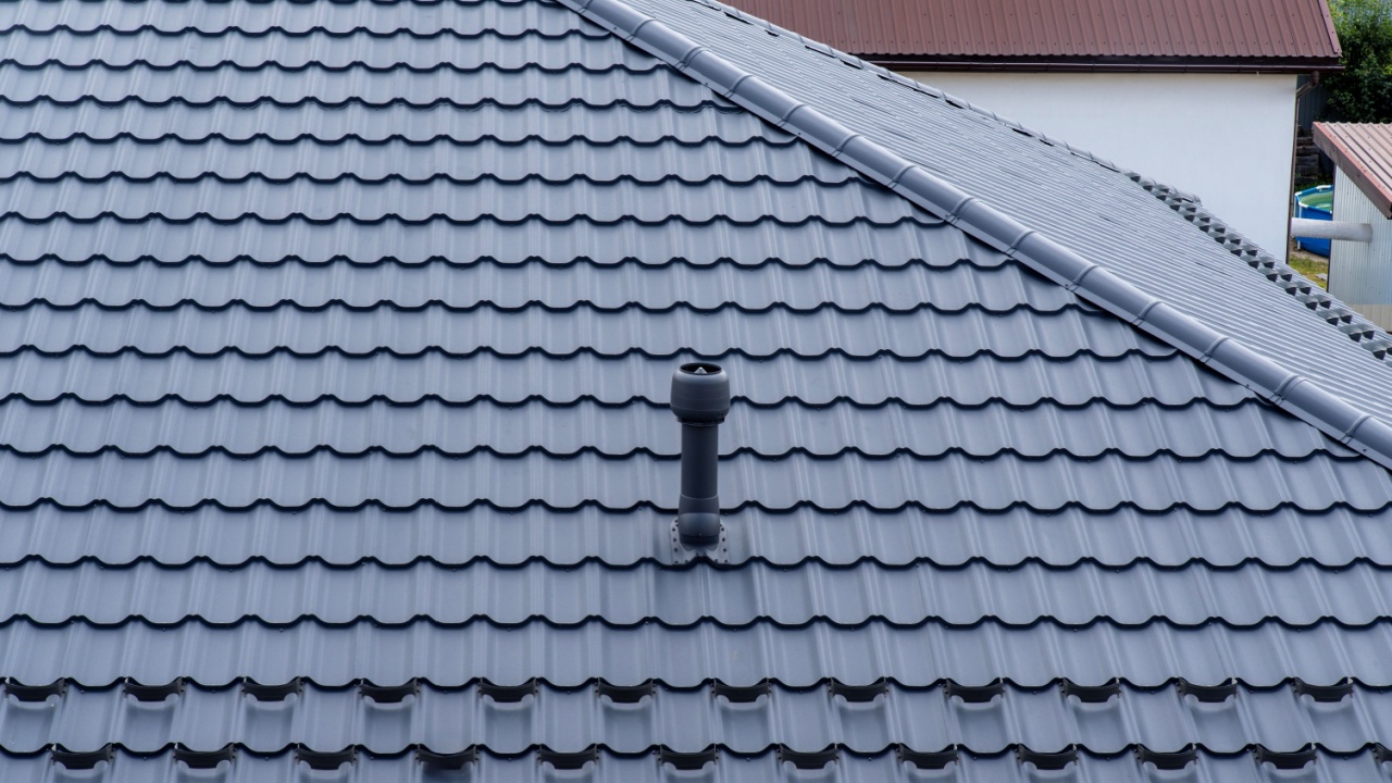 Plastic roof vent pipe on gray metal tile roofing