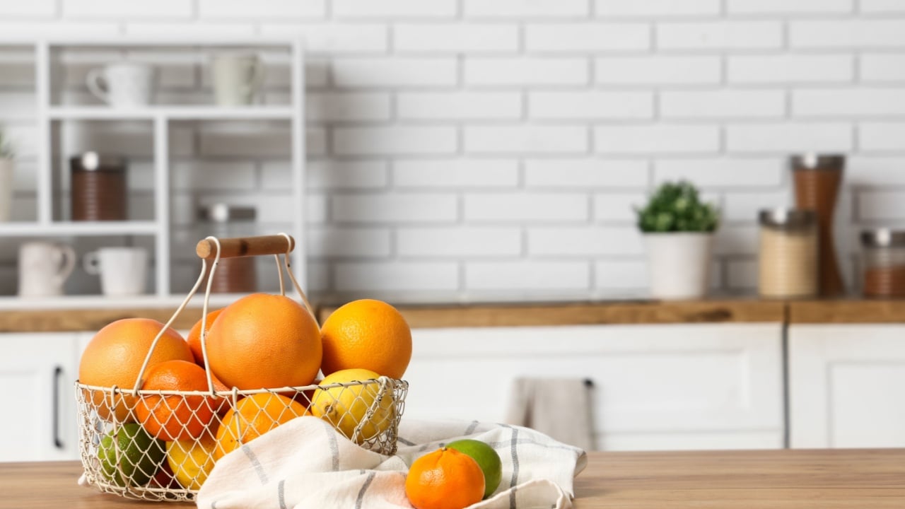 Basket with tasty citrus fruits on table in kitchen