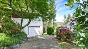 House exterior. View of garage and driveway. Around blossom flowers