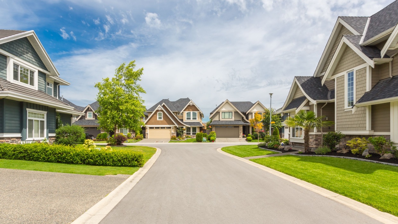 Nicely trimmed and manicured garden in front of a luxury house on a sunny summer day. Street of houses in the suburbs of Canada.