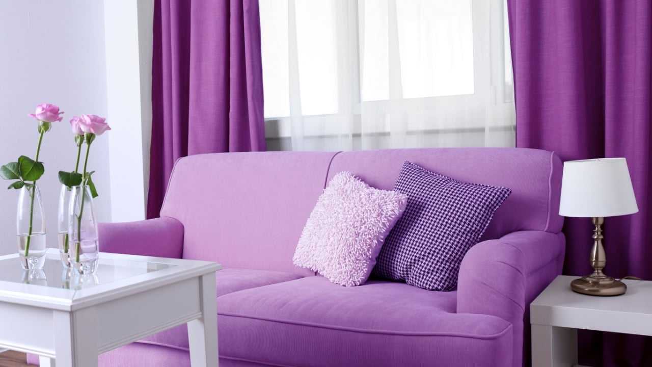 Lilac color accent in modern interior. Comfortable couch and table with flowers in living room