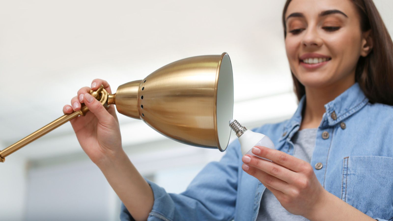 Woman changing light bulb in lamp indoors