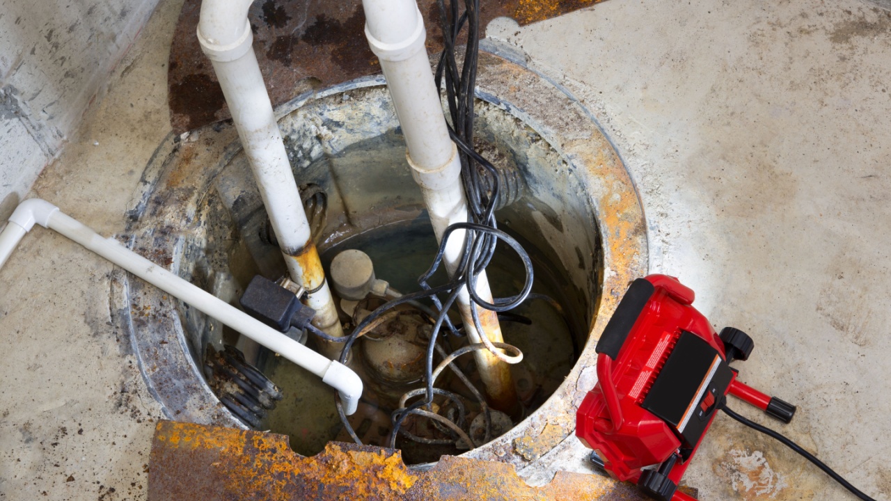 Repairing a sump pump in a basement with a red LED light illuminating the pit and pipe work for draining ground water