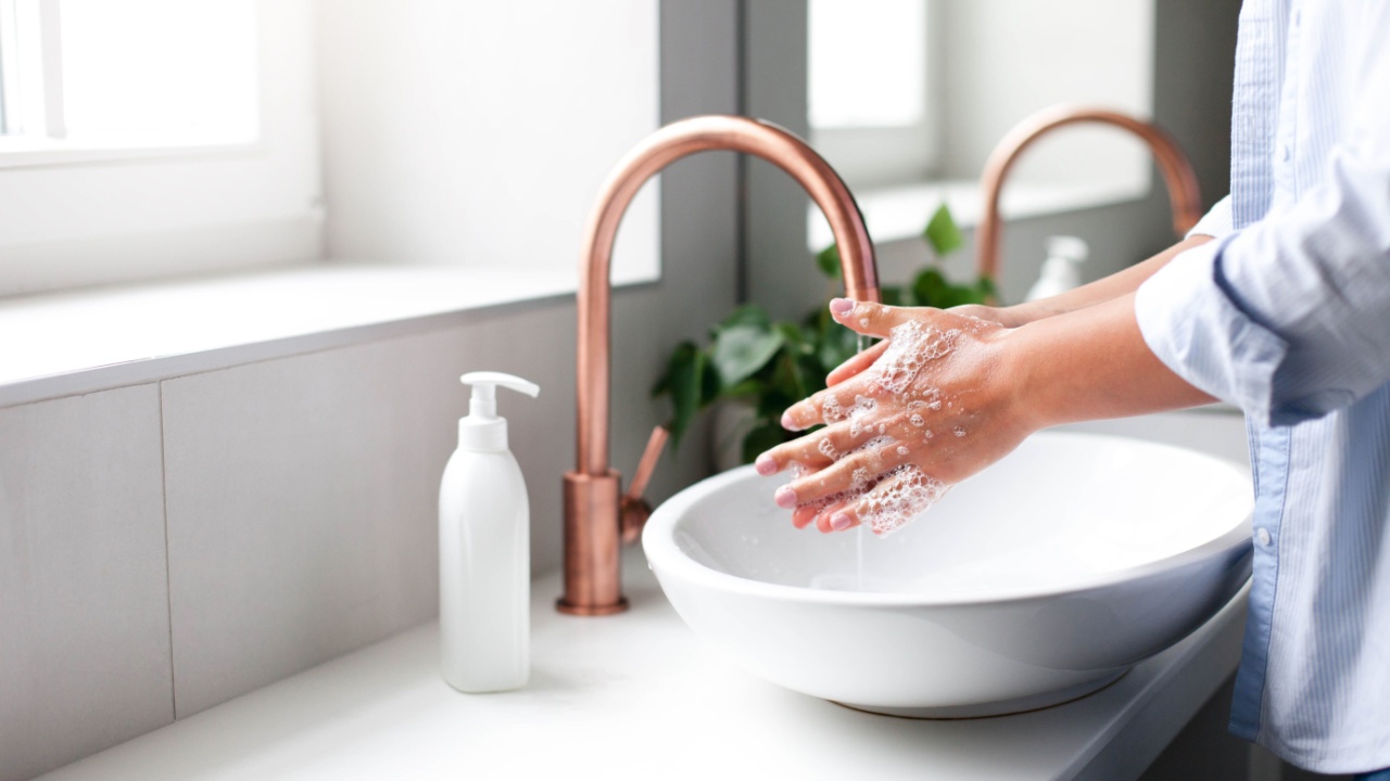 Woman washing hands under water tap. Self care and hygiene. Close up of female hand. Infection prevention. Liquid antibacterial soap and foam.