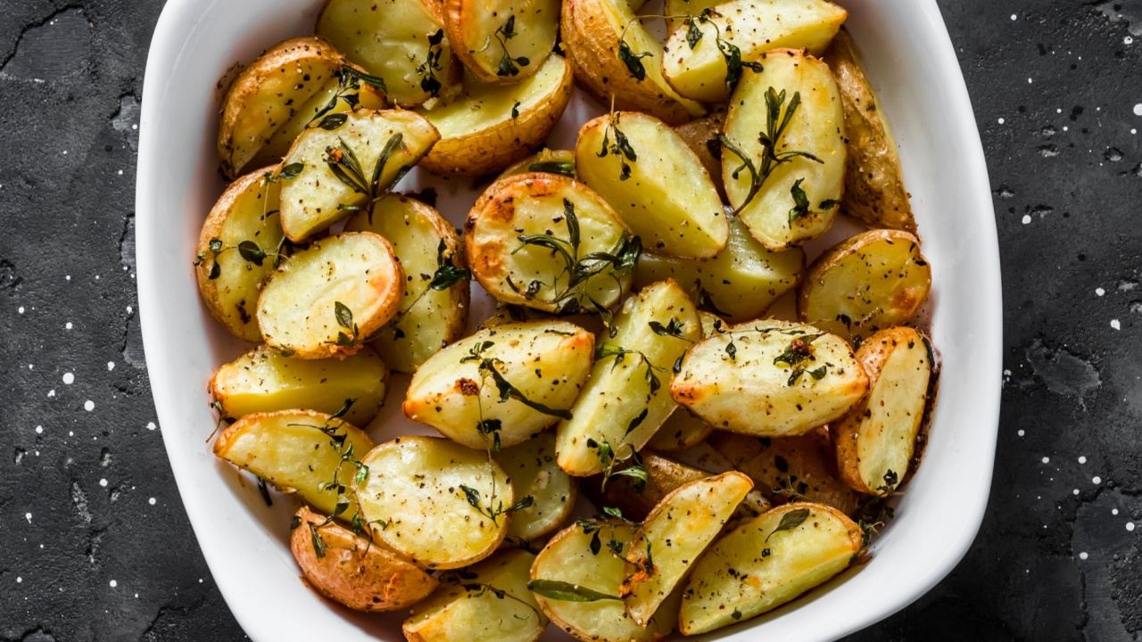 Rosemary fried new potatoes on a dark background, top view