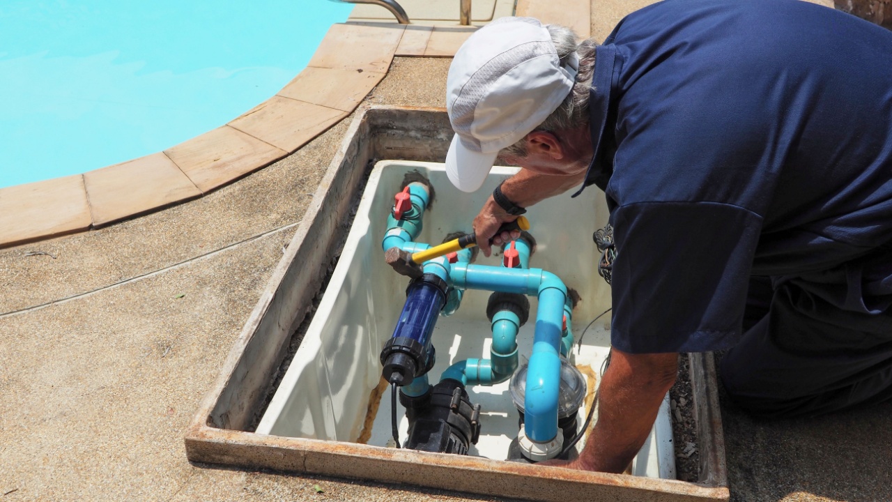 Technician fixing swimming pool water pump. Service and maintenance for swimming pool.