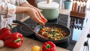 Woman frying vegetables in kitchen
