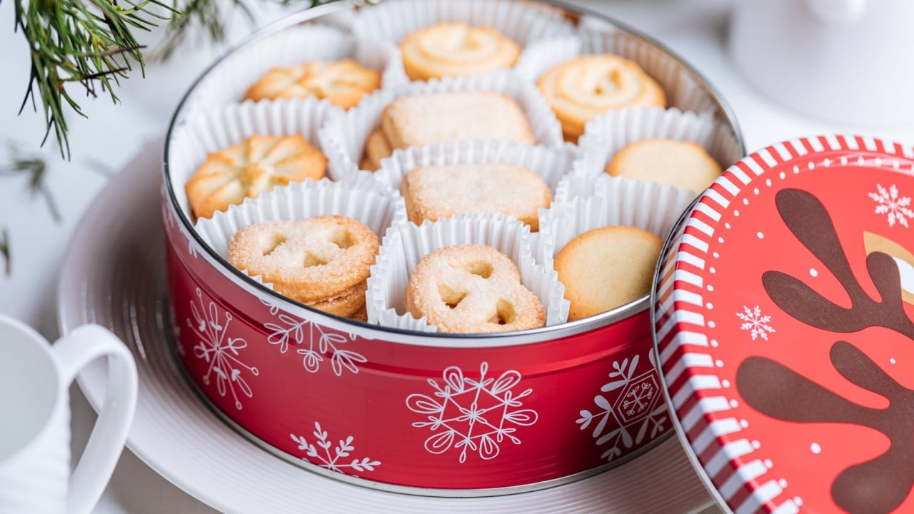 Danish butter cookies in a red Christmas tin box with the snowflakes and deer illustration. Holiday tea cake cookies.