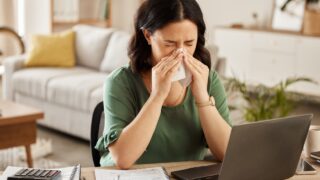 Laptop, remote work and sick woman in home office with flu, cold or viral infection in her house. Freelance, sneeze and lady online with allergy, virus or burnout, sinusitis or hayfever while typing