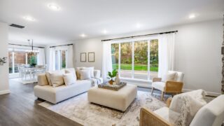 Interior living room with fireplace stone and wood mantle staircase wooden flooring decorated and staged large bright windows classic and modern decor