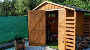 A wooden garden shed standing on a concrete foundation in a garden.