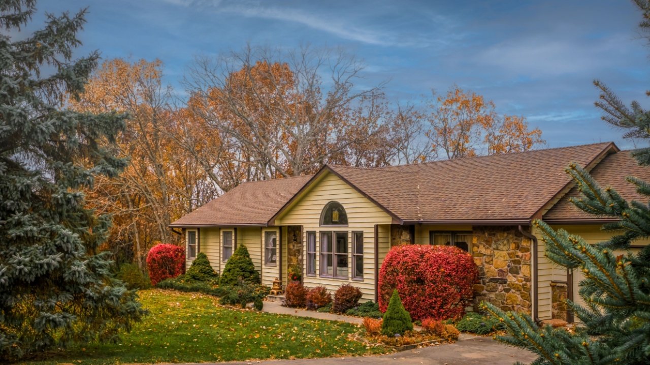View of Midwestern house in fall with front yard in foreground and blue sky in background