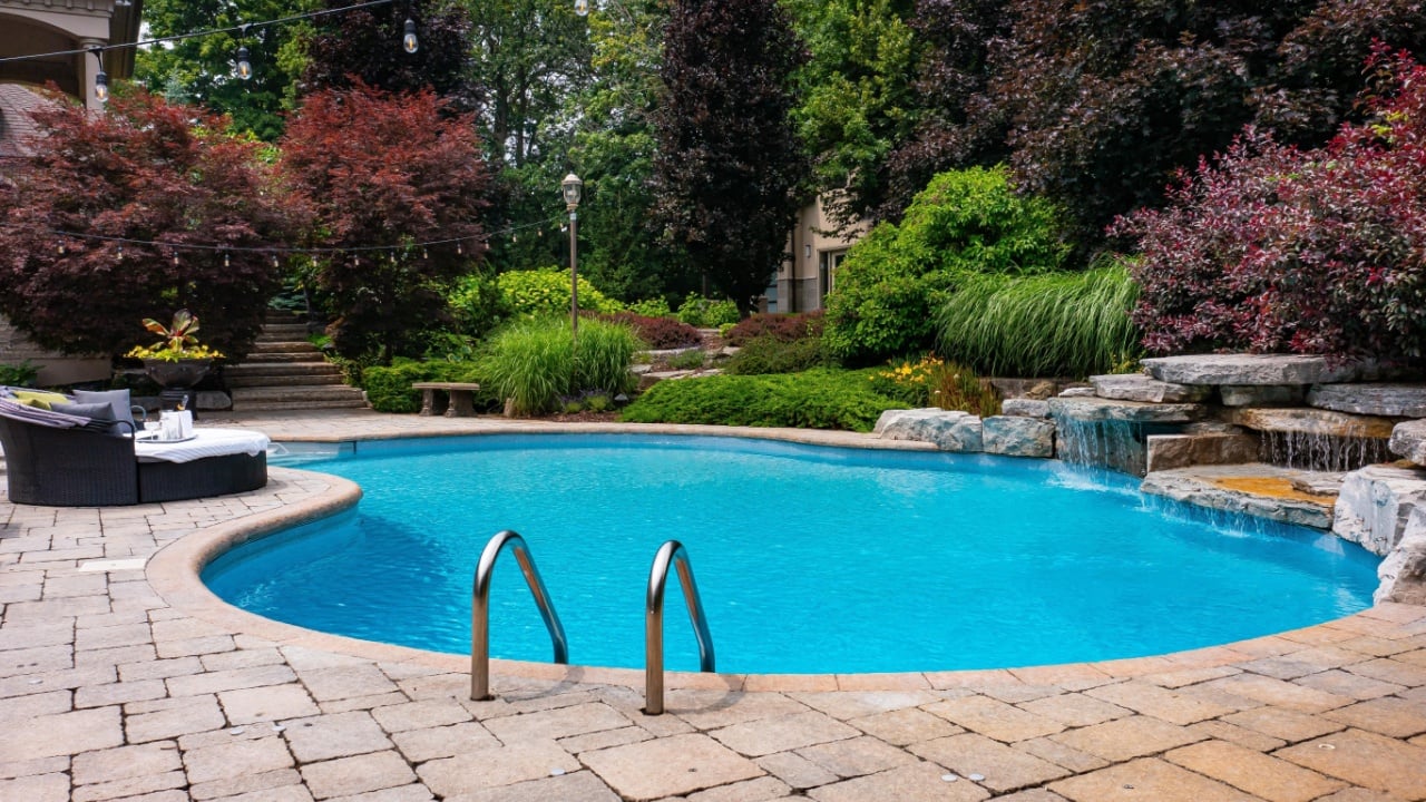 Dive into luxury with this stunning photo featuring a lavish swimming pool, exquisite house, lush green backyard, and meticulously designed garden. Experience the pinnacle of opulence and tranquility.