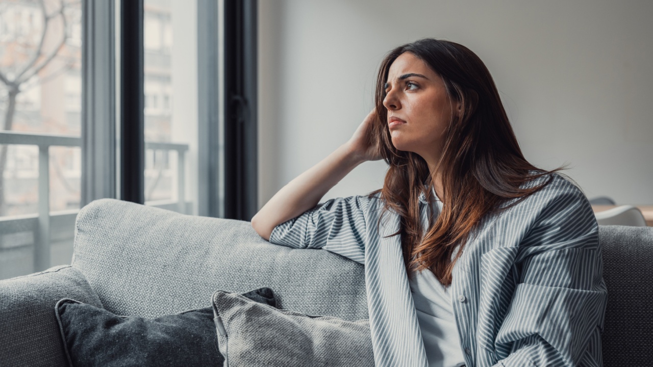 Close up of sad pensive millennial woman sit alone thinking about relationships personal problems, upset thoughtful young female lost in thoughts feel lonely depressed pondering or mourning at home