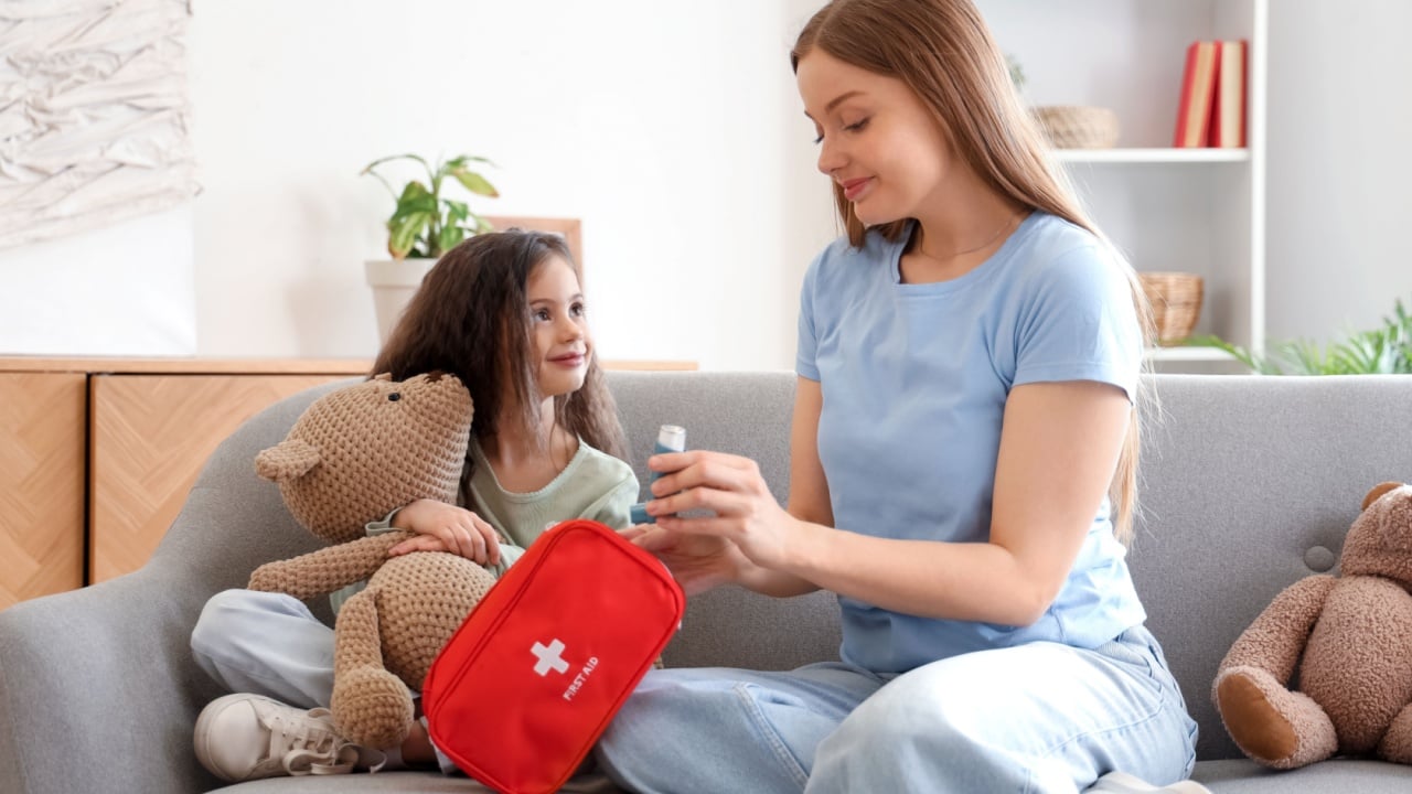 Little girl with toy and her mother taking inhaler from first aid kit at home