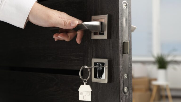 Woman opening door with key and house shaped keychain, closeup
