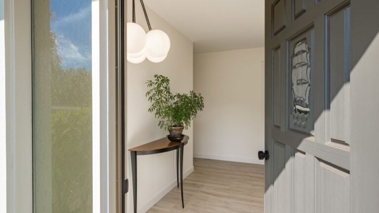 foyer entry wooden door ajar black front door cedar ceiling warm welcoming side light window welcome mat bench light fixture wall sconce lighting welcoming front door