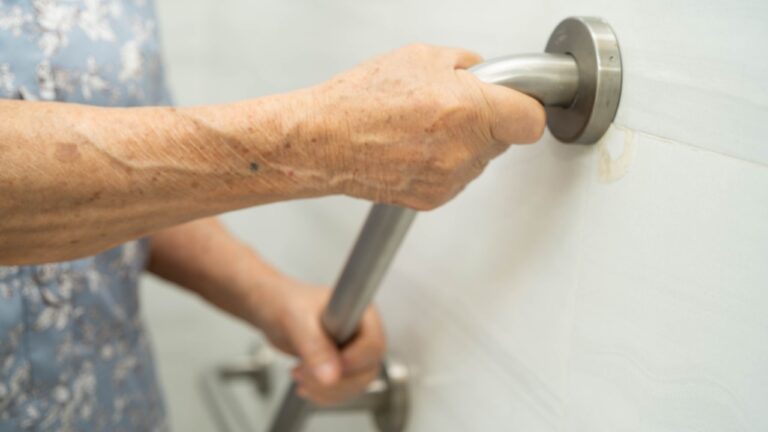 Asian elderly woman use safety handrail in bathroom.