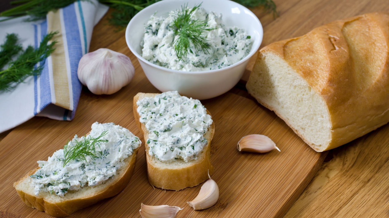 Slices of baguette with cottage cheese parsley, garlic on a cutting board. Curd sandwich in a bowl.