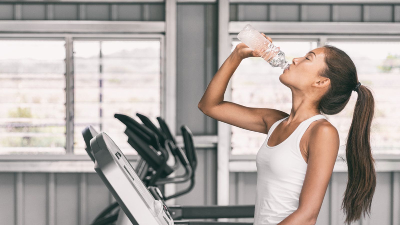 gym workout fitness woman drinking water bottle treadmill exercise