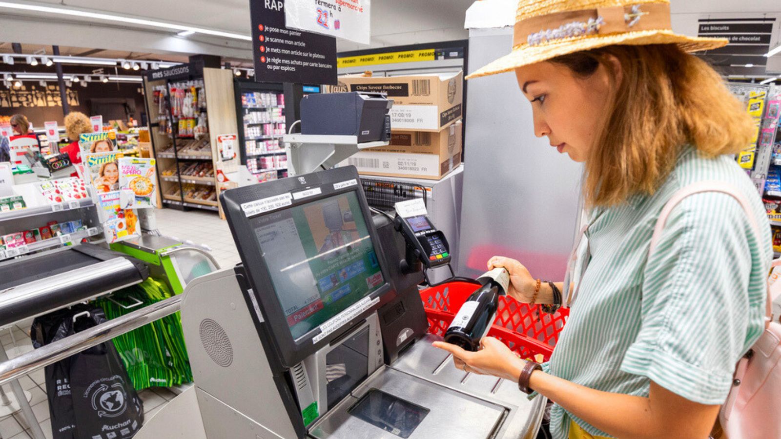Auchan supermarket, Lyon, France Girl customer scans products at the self-service checkout in the grocery supermarket shop