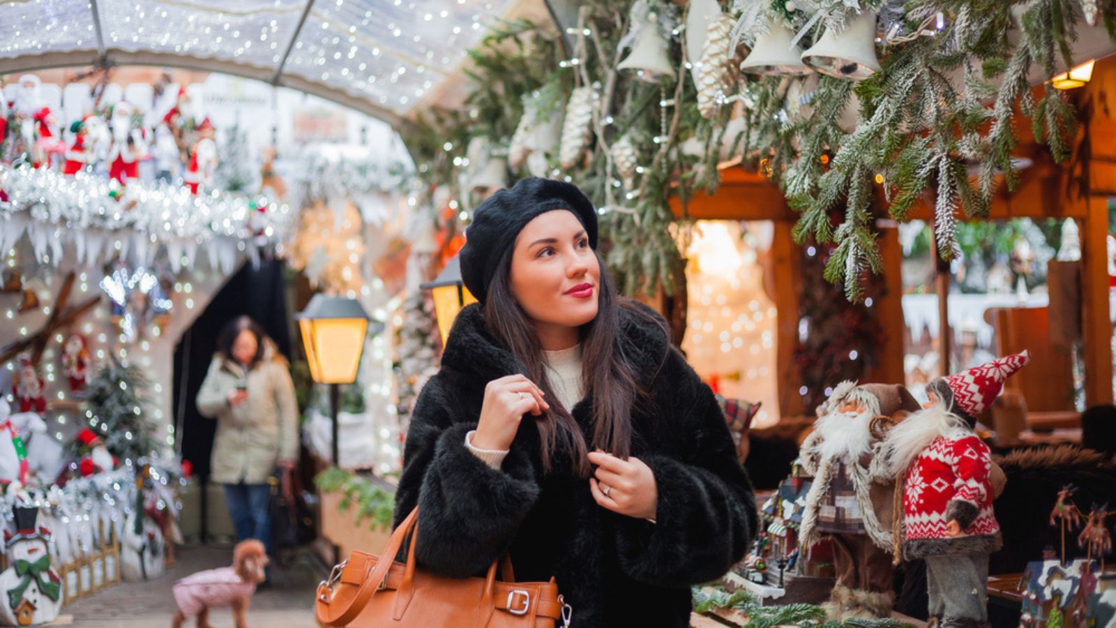 Beautiful dark-haired young woman in an eco fur coat walks around the city and does Christmas shopping. New Year holidays. Present. Holidays