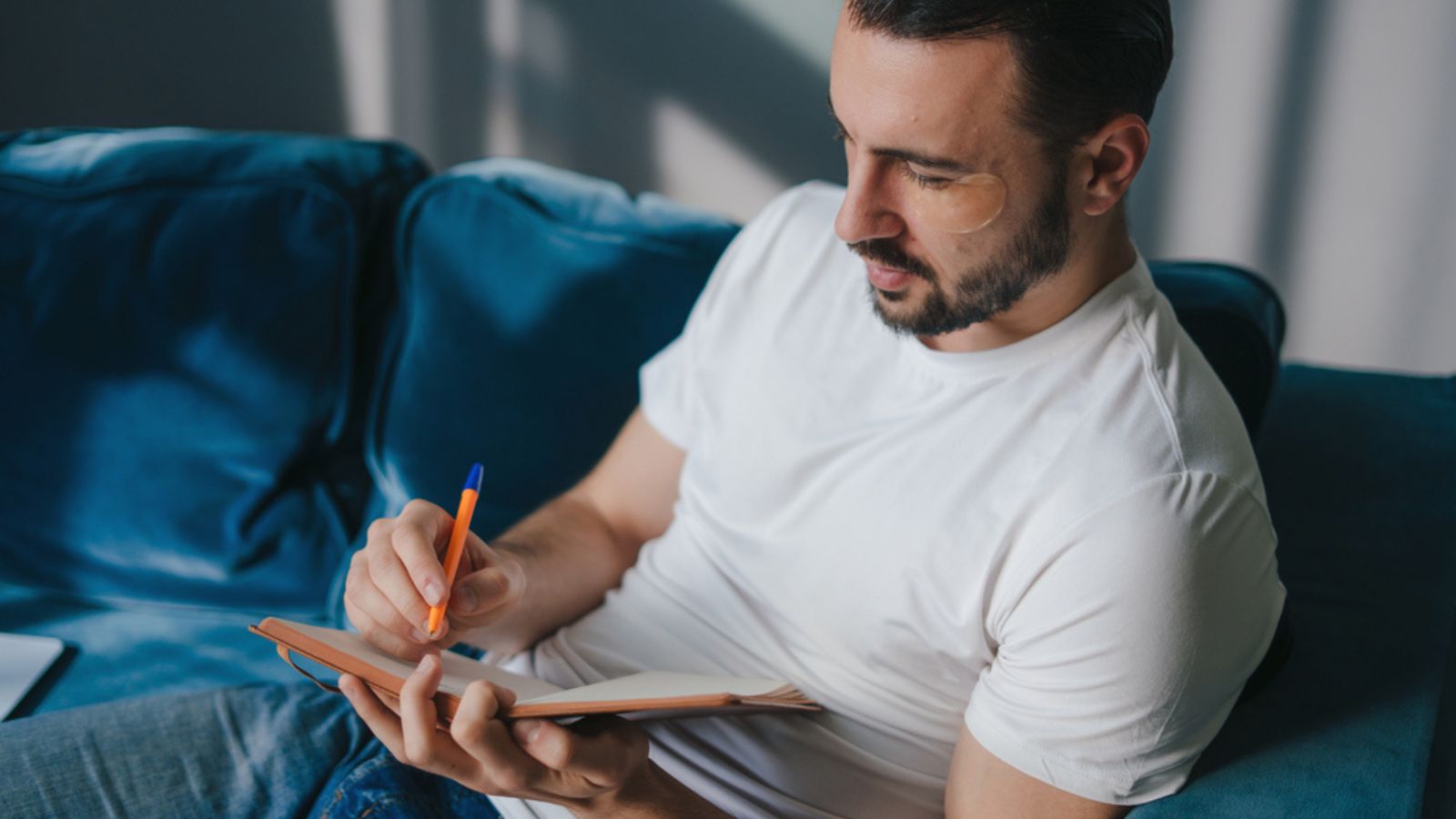 Caucasian man writing down thoughts in journal. Creativeman making notes in a notepad.
