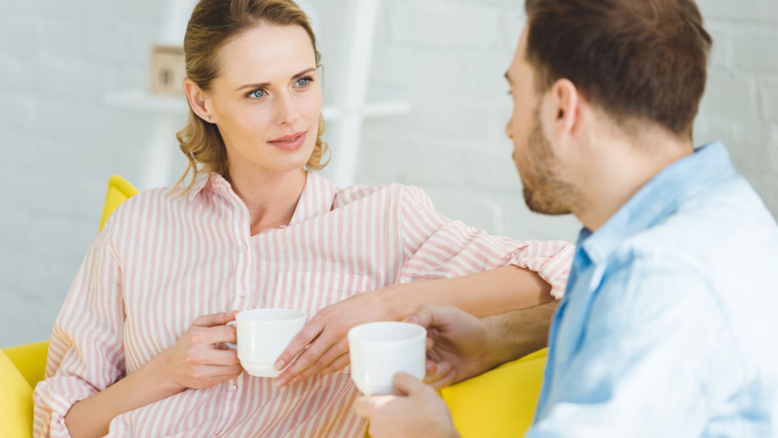 Couple talking and holding cups of tea in hands