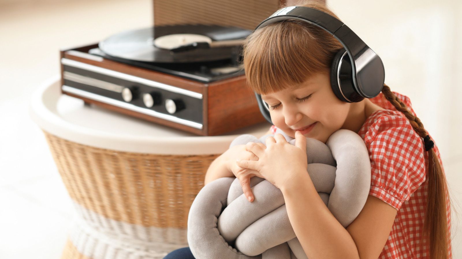 Cute little girl listening to music through record player at home