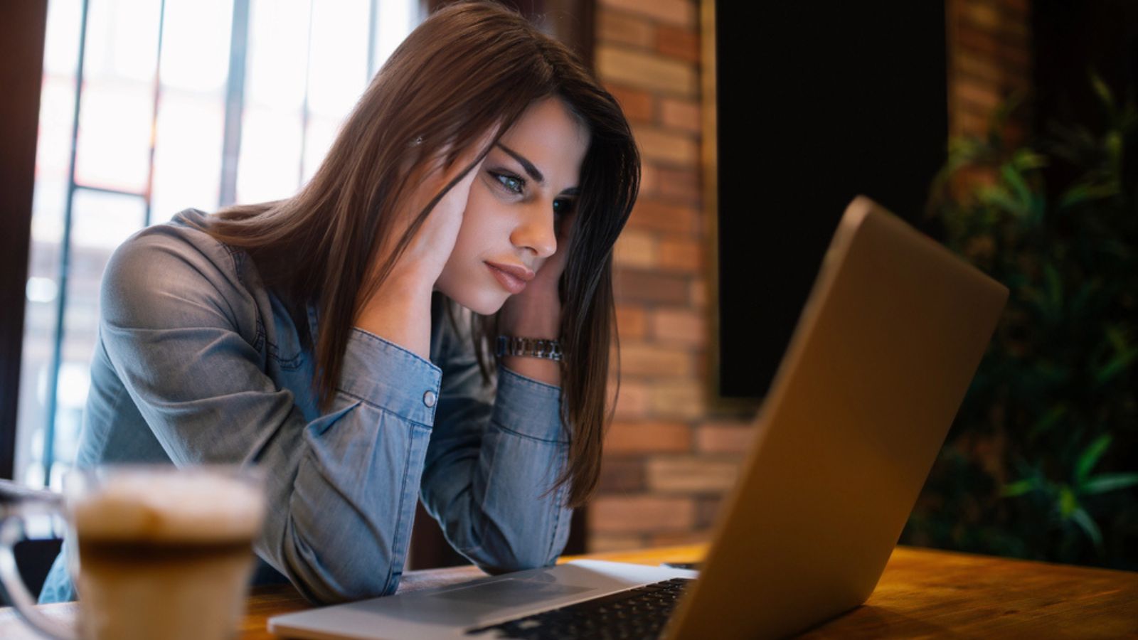 Frustrated worried young woman looks at laptop upset by bad news, teenager feels shocked afraid reading negative bullying message, stressed girl troubled with problem online or email notification