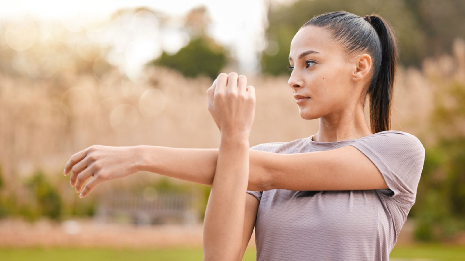 Health, fitness and woman stretching arms in nature to get ready for workout, training or exercise. Sports, thinking and female athlete stretch and warm up