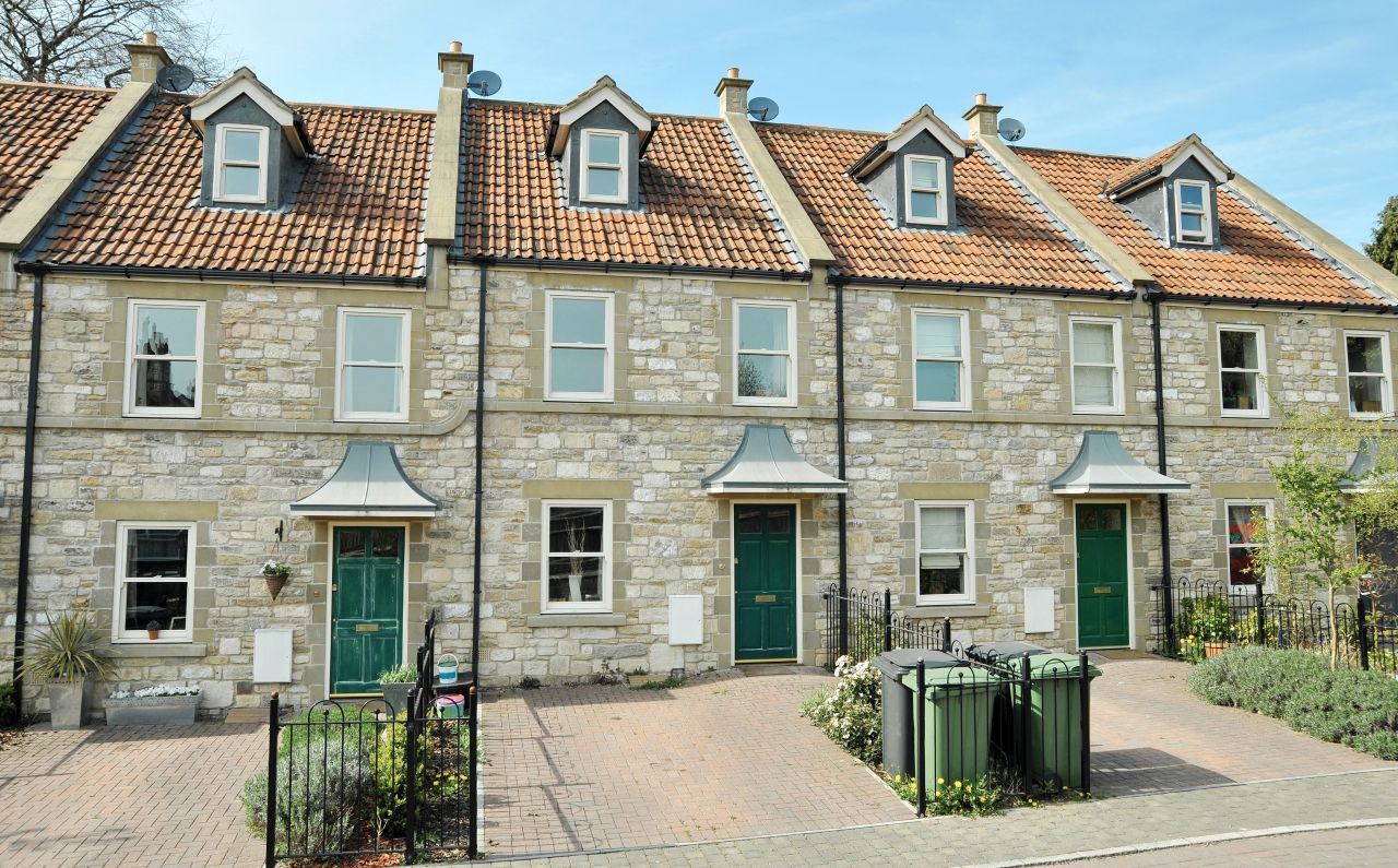 Row of traditional terraced stone cottages along a quiet street in an English town.