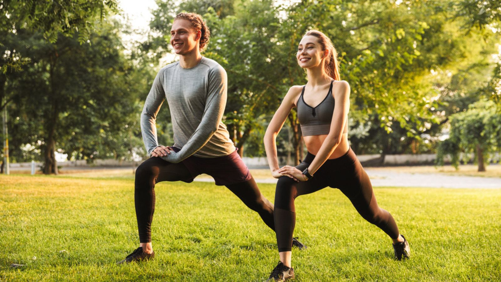 Image of strong fitness sport loving couple friends in park outdoors make stretching exercises