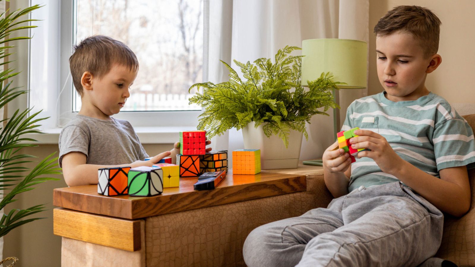 Khabarovsk, Russia. Two male kids brothers assembling Rubiks cube with confident face expression thinking solving logic decision. Sibling child boy playing logical game