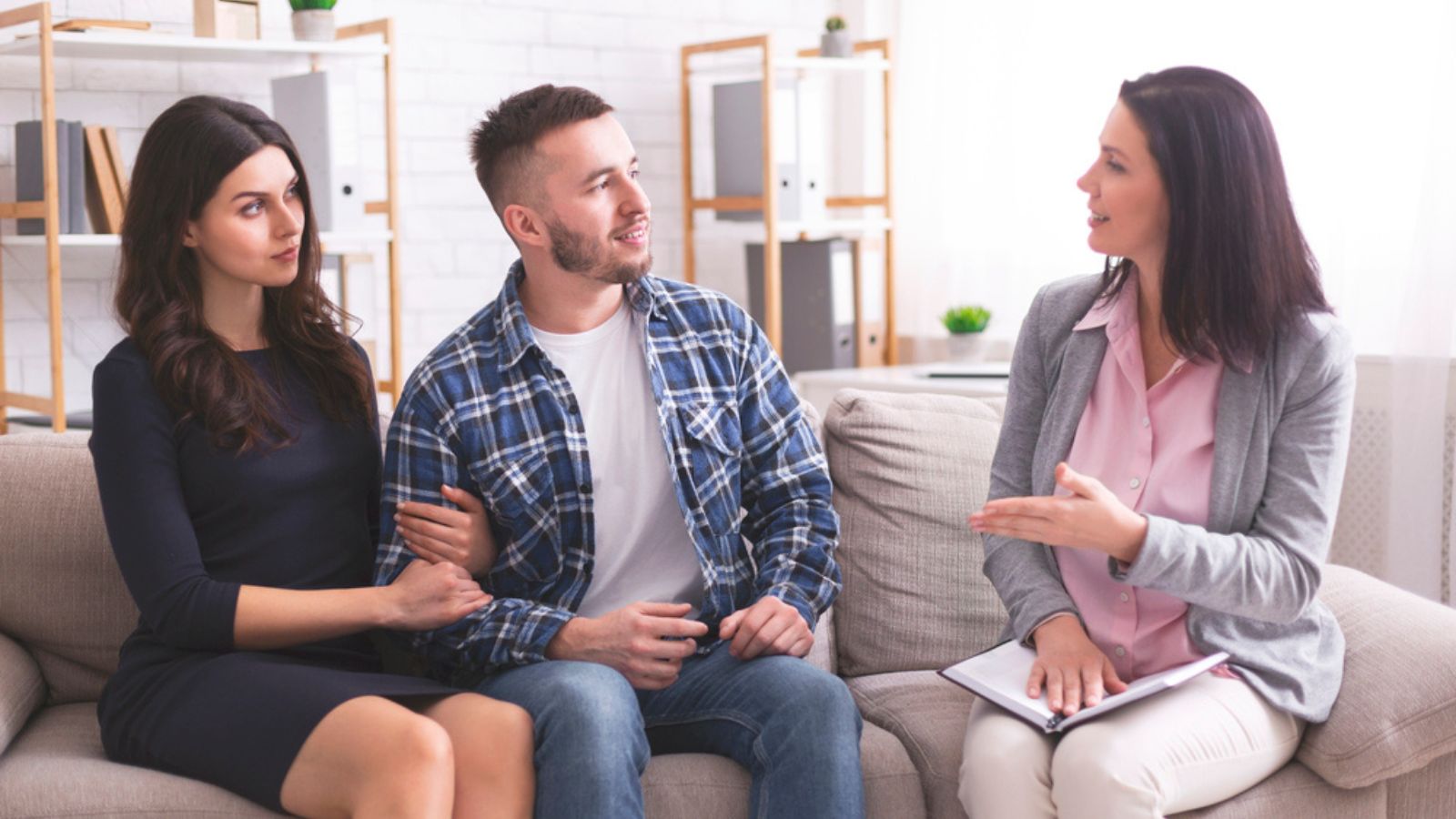 Millennial spouses talking with psychotherapist at office