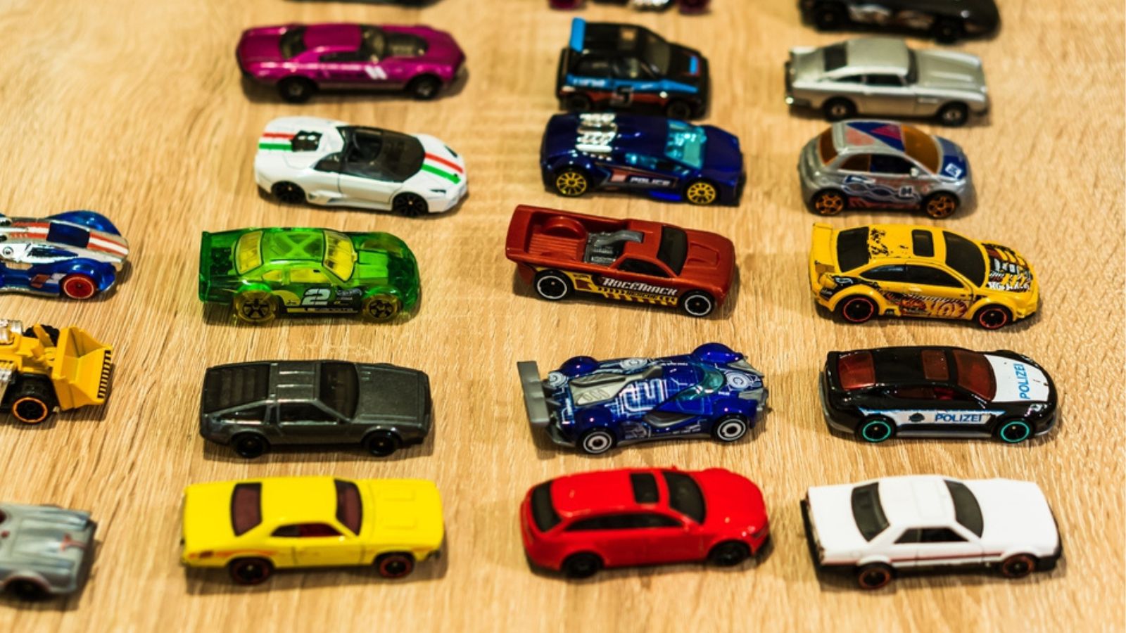 Mix of different Mattel Hot Wheels toy cars on a wooden surface in soft focus