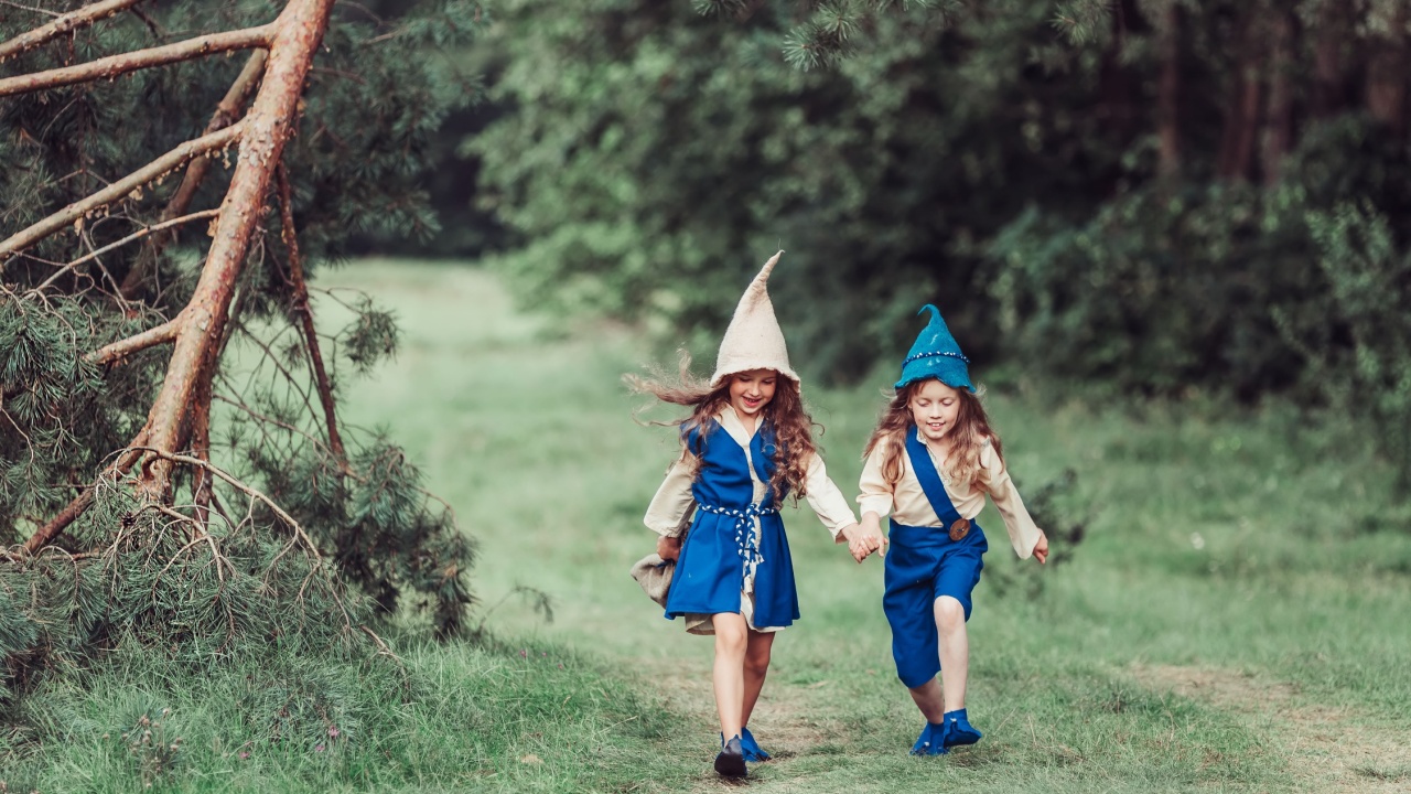 Little happy girls in a gnome hat having fun in a green forest in the summer have a nice day. Childhood, nature and happiness concept