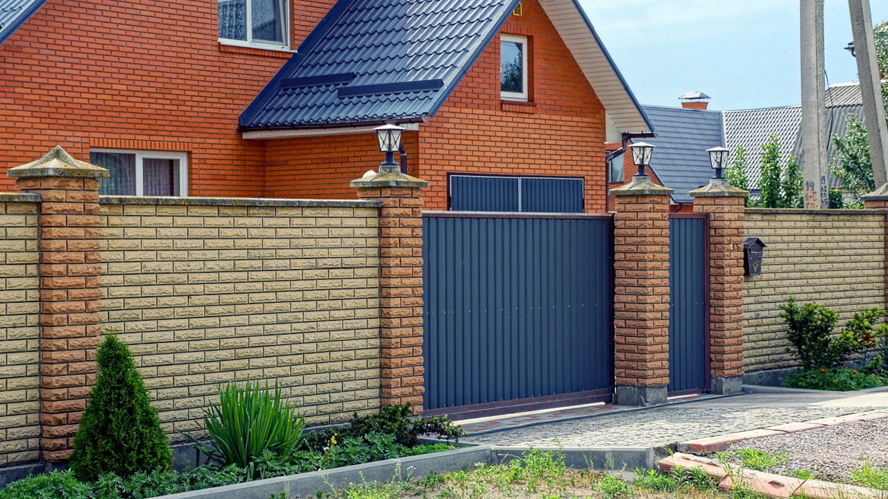 Long modern brown fence made of bricks and iron on the street in front of the road
