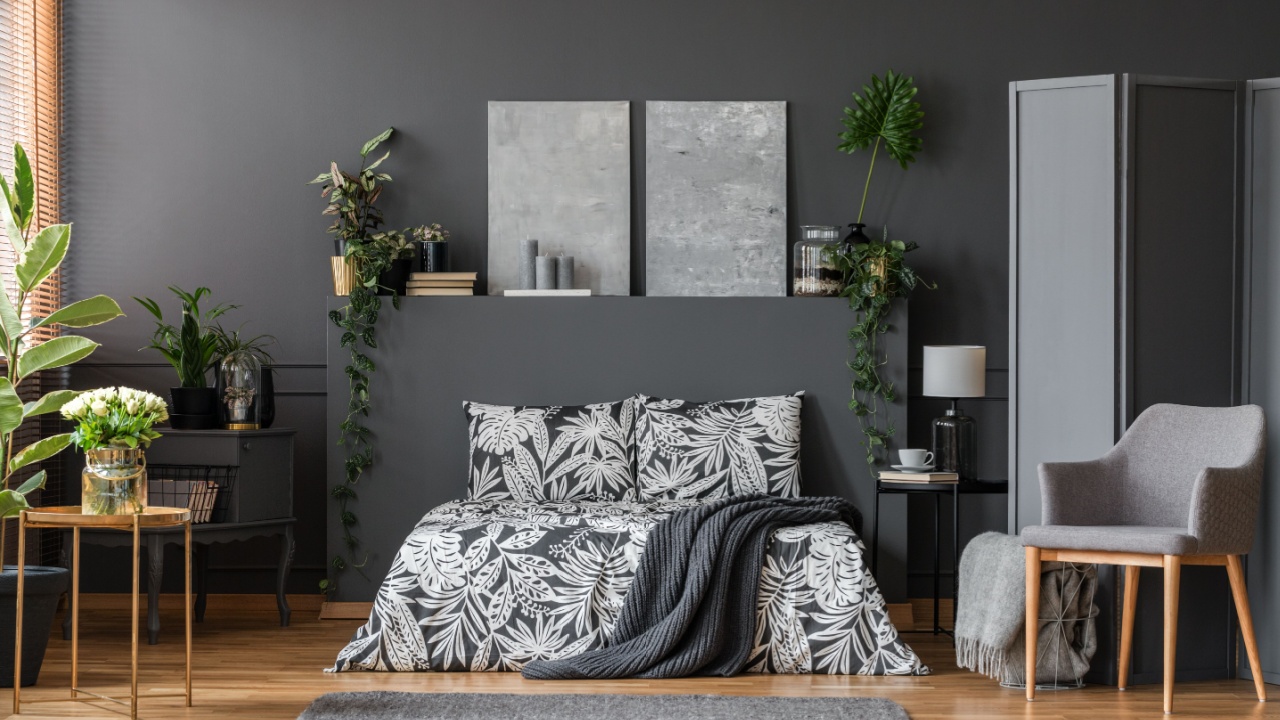 Modern gray armchair with wooden legs and a room divider panel in an elegant bedroom interior with dark decor