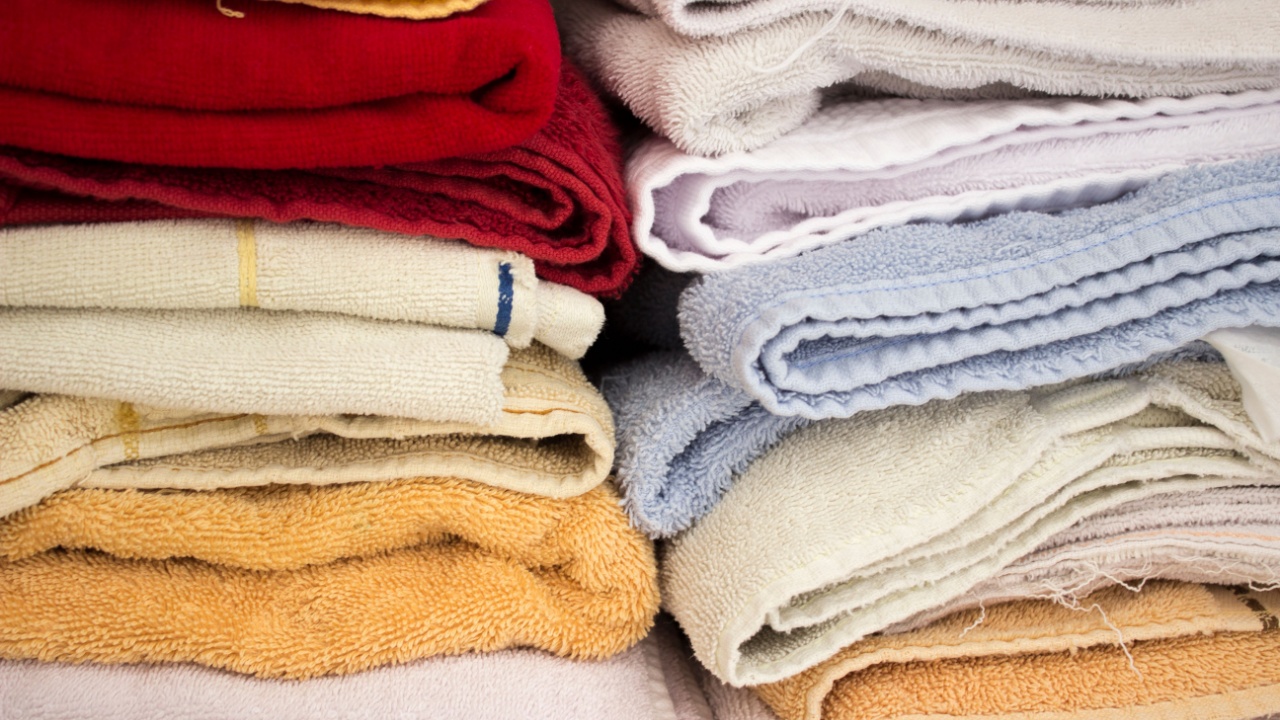 Stacked colorful household towels. There are red, blue and yellow, and they're stacked in a closet.