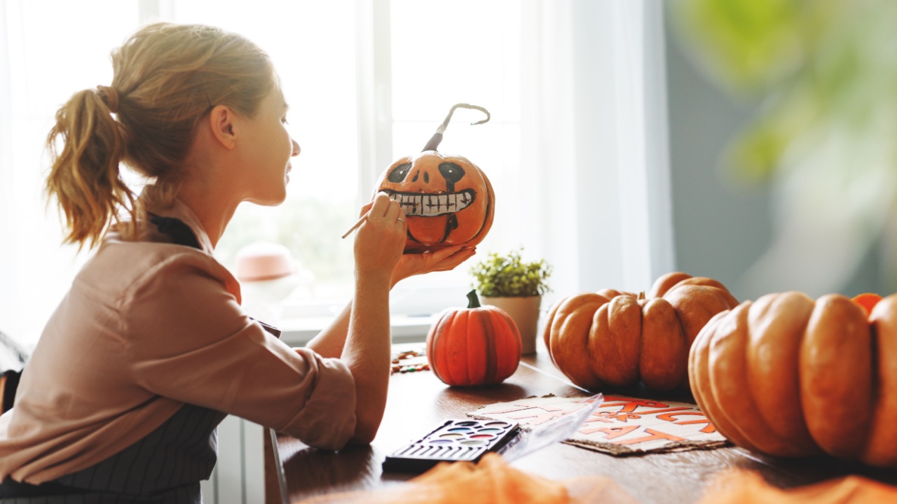 a woman artist prepares for halloween and paints pumpkins