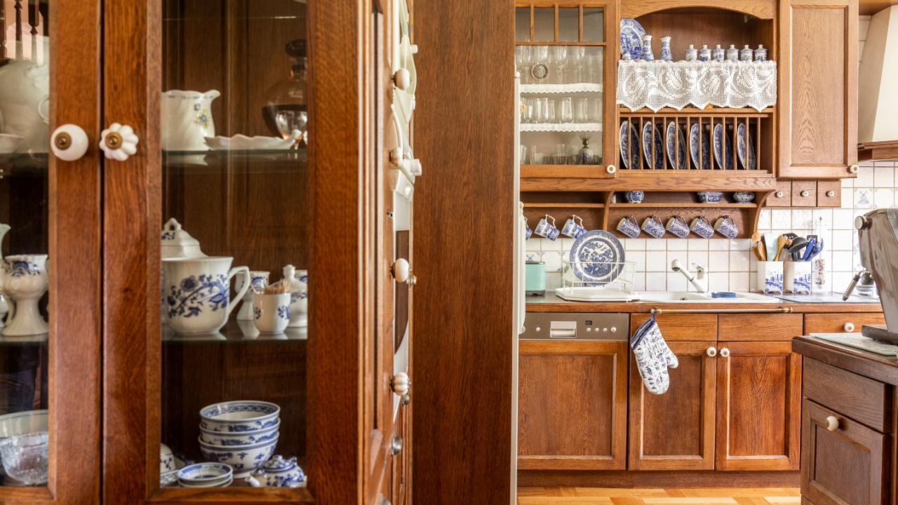 Old fashioned wooden cabinets with white and cobalt blue china in kitchen interior.
