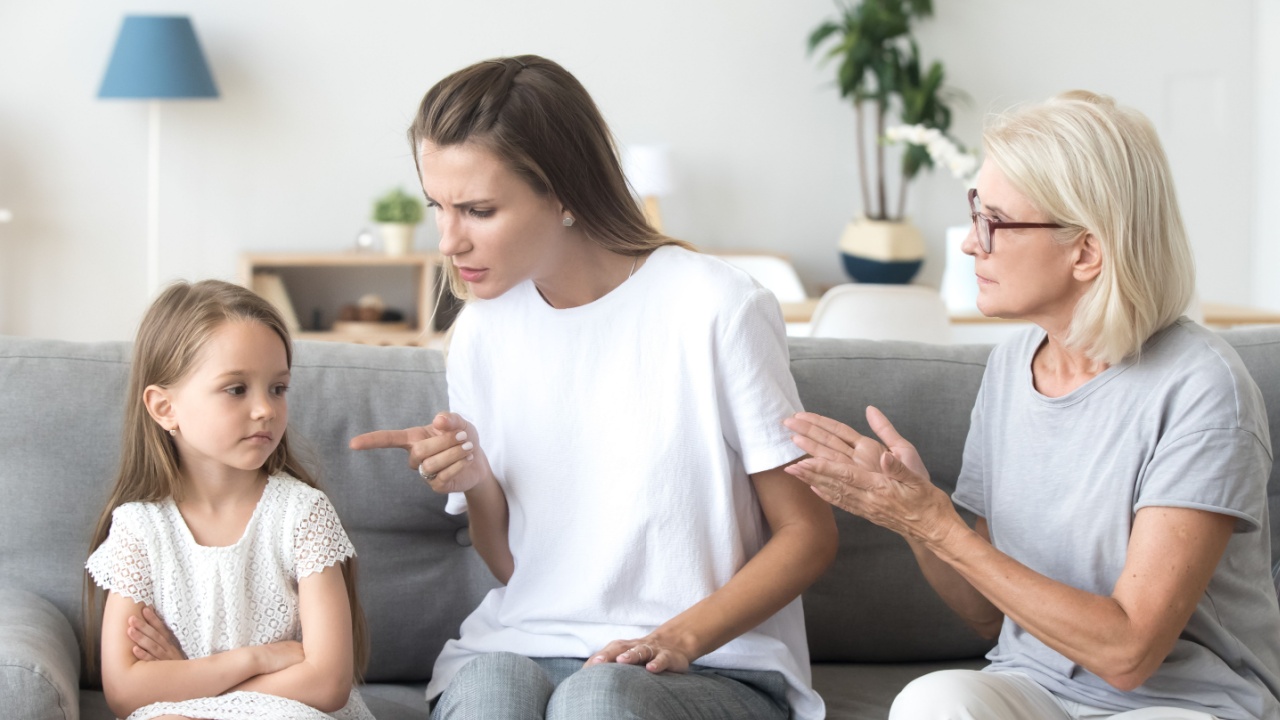 Angry young mother scolding child daughter while old grandmother interfering when strict mom lecturing little girl, three generations disagreements affecting upbringing kid, family conflicts concept