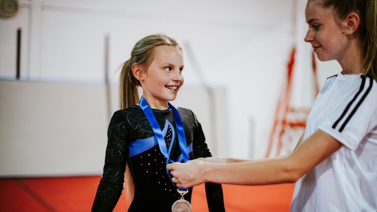 Coach giving a silver medal to a young gymnast