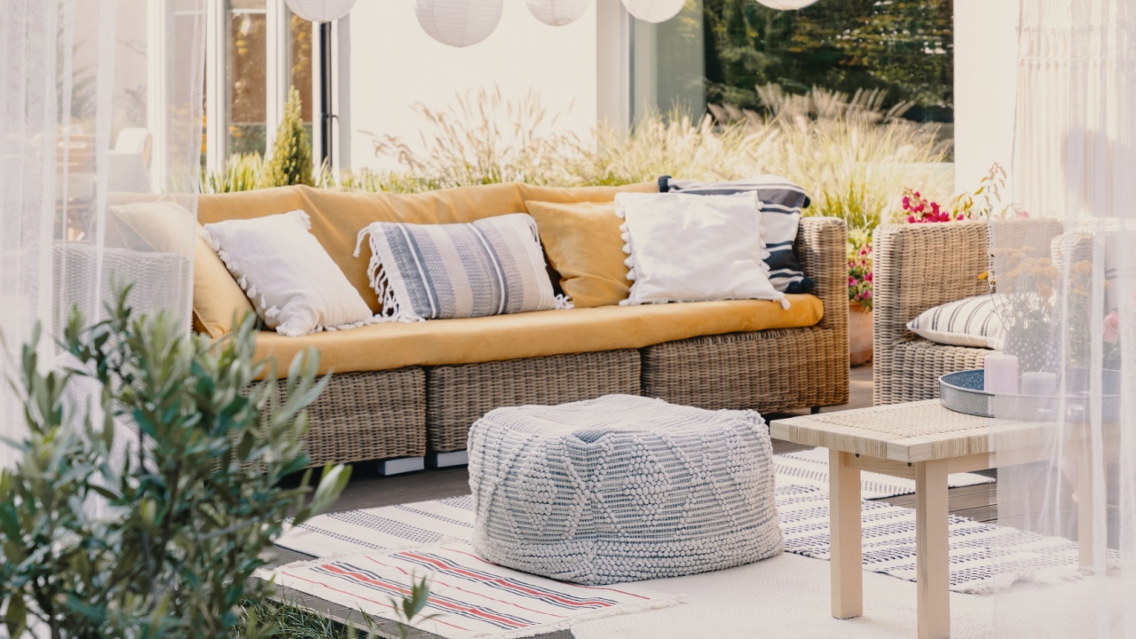 Stylish outdoor relax area with garden furniture and comfortable pouf, real photo
