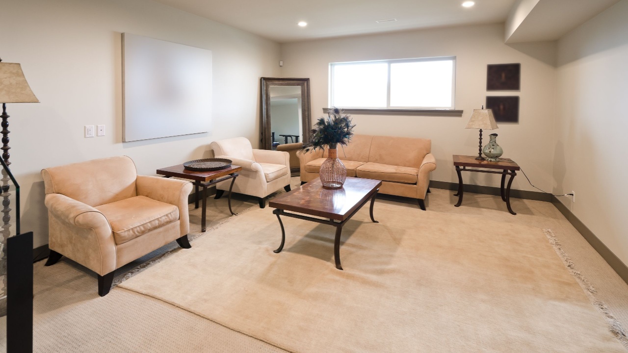 Interior of the modern nicely decorated living room in the basement. Two coaches, sofa and the table on the big rug. Interior design.