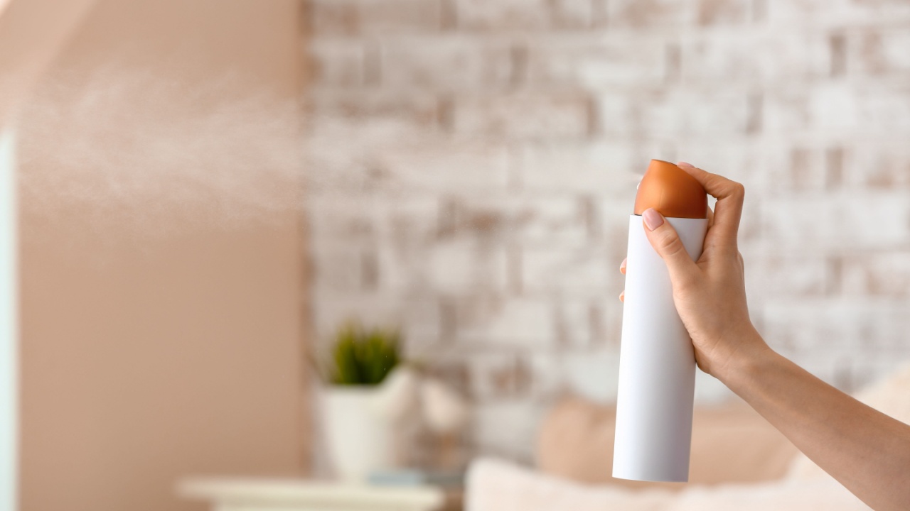Woman spraying air freshener in room