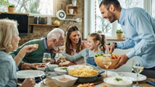 Happy multi-generation family gathering around dining table and having fun during a lunch.