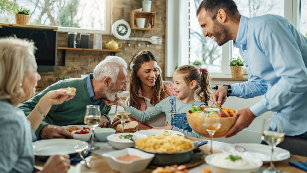 Happy multi-generation family gathering around dining table and having fun during a lunch.