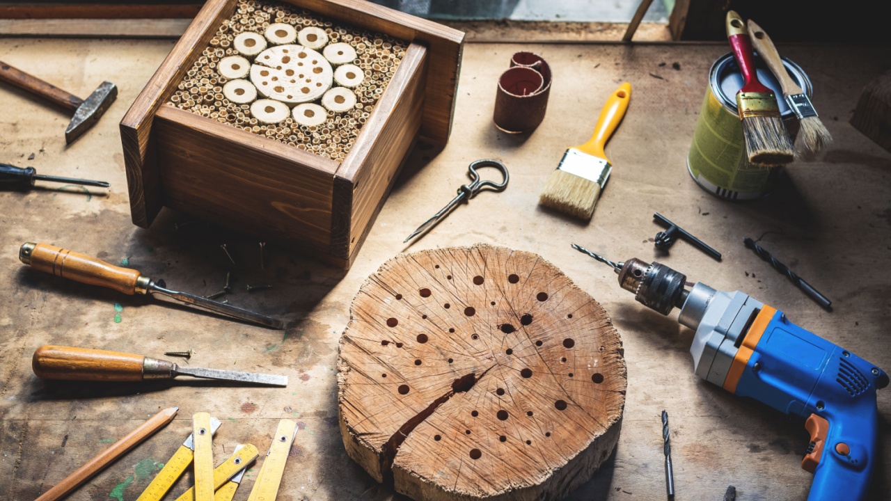 Making wooden insect hotel or house in workshop. DIY and work tools on table. Drill, chisel, paintbrush, hammer and decorative craft product